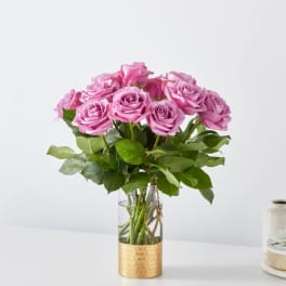 Pink roses arranged in a clear glass vase with a gold base