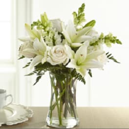 White lilies and roses arranged in a clear glass vase