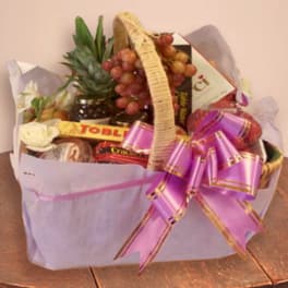 Gift basket with fruit, chocolates, and a purple ribbon