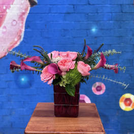 Pink roses and calla lilies in a dark glass vase