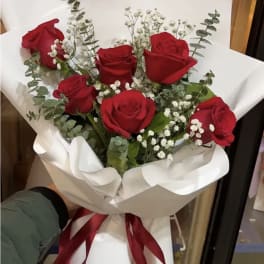 Bouquet of red roses with white baby's breath wrapped in white paper