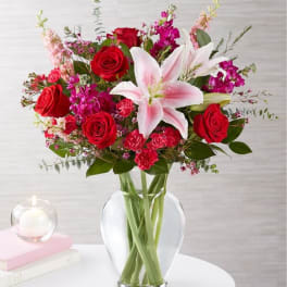 Bouquet of red roses and pink lilies in a clear glass vase