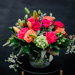 Bright mixed bouquet in a glass vase with pink and peach blooms
