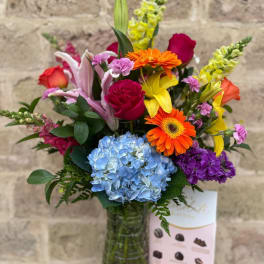 Colorful mixed bouquet in a glass vase with roses, lilies, gerbera daisies, and hydrangea