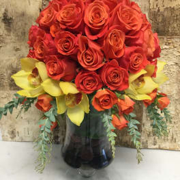 Bouquet of red roses and yellow orchids in a glass vase