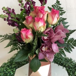 Pink roses and purple orchids in a geometric rose-gold vase