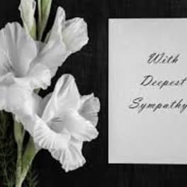 White flowers beside a sympathy card on a black background