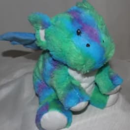 A blue, green, and purple plush teddy bear sitting on a white surface.