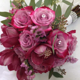 Hand-tied bouquet of pink roses and burgundy orchids with jeweled accents and a wrapped handle