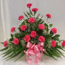 Pink carnations in a white basket with a pink ribbon