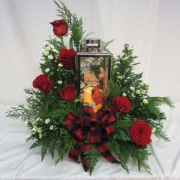 Red roses arranged around a lantern with a plaid bow