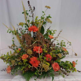 Orange gerbera daisies in a low, wide floral arrangement with dried accents