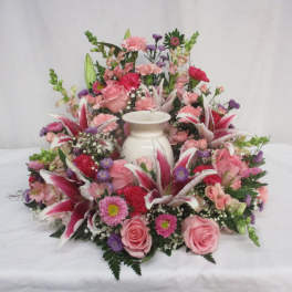 Pink and purple floral arrangement around a white urn