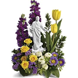 Floral arrangement with a white statue centerpiece, yellow tulips, and purple flowers