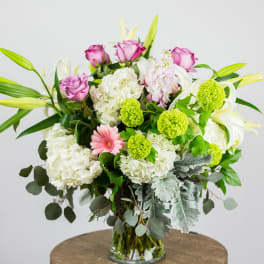 Bouquet of pink roses, white hydrangeas, and lilies in a glass vase