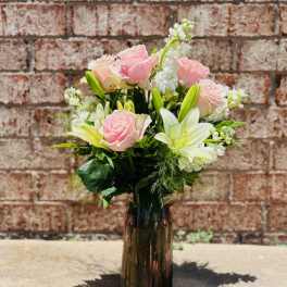 Pink roses and white lilies in a dark glass vase