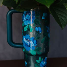 Floral-decorated teal travel mug with blue flowers and green leaves