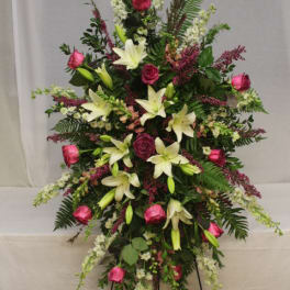 Standing floral spray with pink roses and white lilies on a black easel