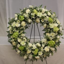 Large white and green floral wreath on a stand