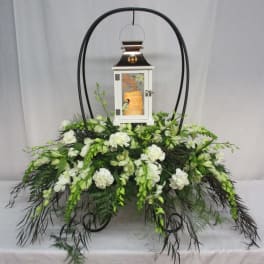 White floral funeral lantern arrangement with a framed lantern centerpiece