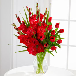 Red tulips and gladiolus in a clear glass vase