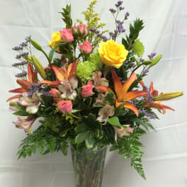 Mixed bouquet of roses, lilies, and alstroemeria in a glass vase