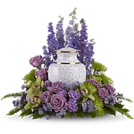 Purple floral arrangement around a white urn vase