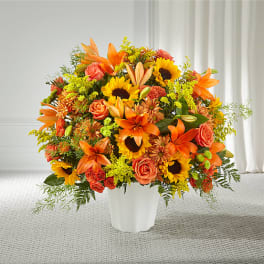 Orange and yellow mixed flower arrangement in a white vase