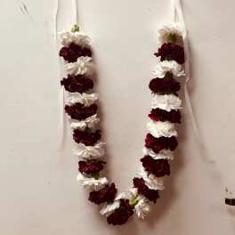 Two white and burgundy flower garlands hang on a wall.