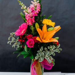 Bright mixed bouquet in a glass vase with pink, orange, and yellow flowers