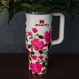 Floral-decorated Stanley tumbler holding greenery and pink flowers