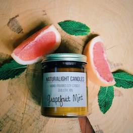 Jar candle with grapefruit slices and mint leaves on a wooden surface