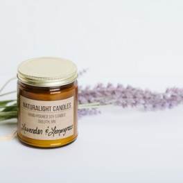 Amber jar soy candle with gold lid beside lavender sprigs on a light surface