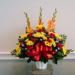 Colorful flower arrangement in a white vase with a red bow