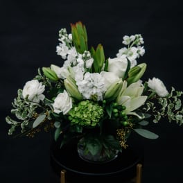 White floral arrangement with lilies and roses in a glass vase