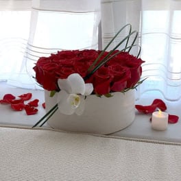 Red roses in a white round box with a white orchid accent