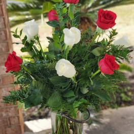 Red and white roses arranged in a clear glass vase