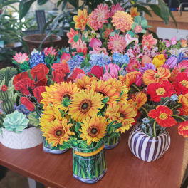 Colorful paper flower arrangements in patterned pots on a table