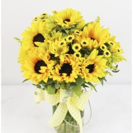 Yellow sunflowers and daisies in a glass vase with a gingham ribbon