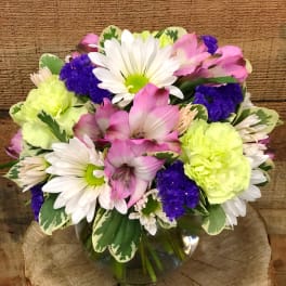 Mixed bouquet of daisies, pink alstroemeria, and carnations in a glass vase