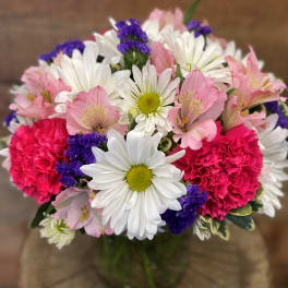 Bouquet of pink and white flowers with purple accents in a glass vase