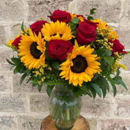 Bouquet of red roses and yellow sunflowers in a glass vase