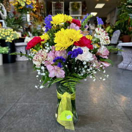 Colorful mixed bouquet in a clear glass vase with a yellow ribbon
