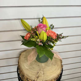Small bouquet with pink rose, lilies, and coral carnations in a green vase