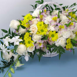 White basket arrangement with white roses, yellow daisies, pink alstroemeria, and orchids