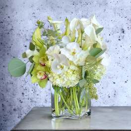 White and pale green floral arrangement in a clear glass vase