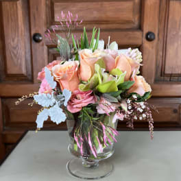 Peach and pink roses arranged in a clear glass vase