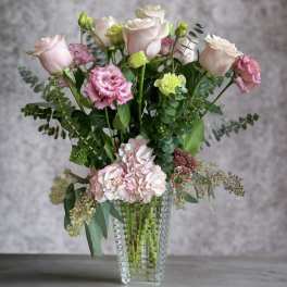 Pink roses and carnations in a clear glass vase