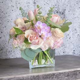 Pastel bouquet of roses, tulips, and orchids in a clear glass vase