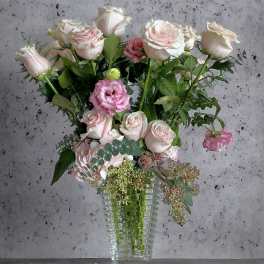 Pink and white roses with pink lisianthus in a clear glass vase